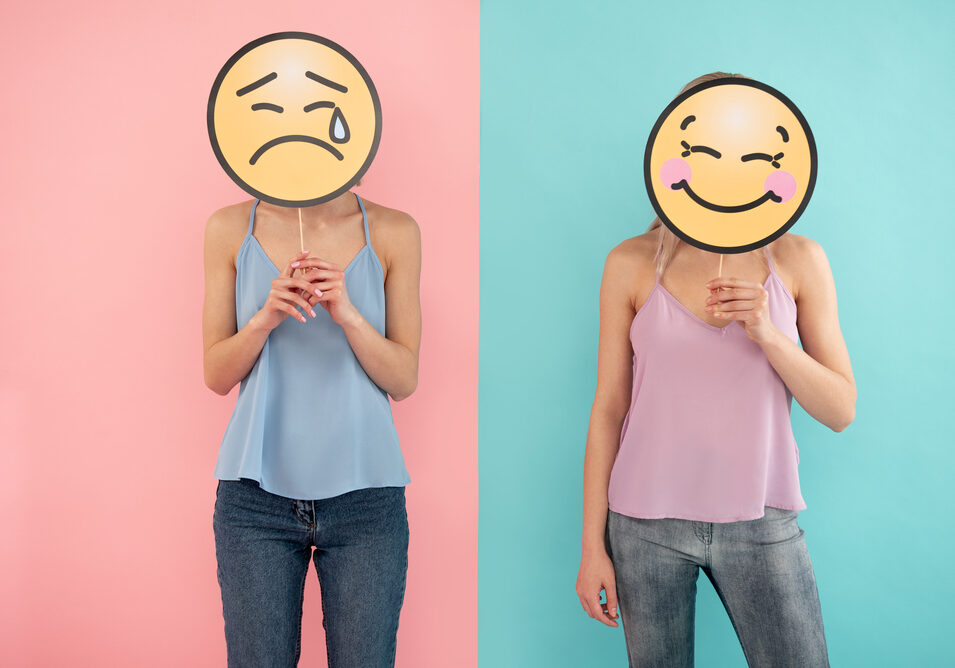 Waist up of smiling and crying female friends posing together. blue and pink background